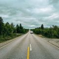 Furgone mentre percorre una strada in Finlandia che taglia una foresta di pini e betulle