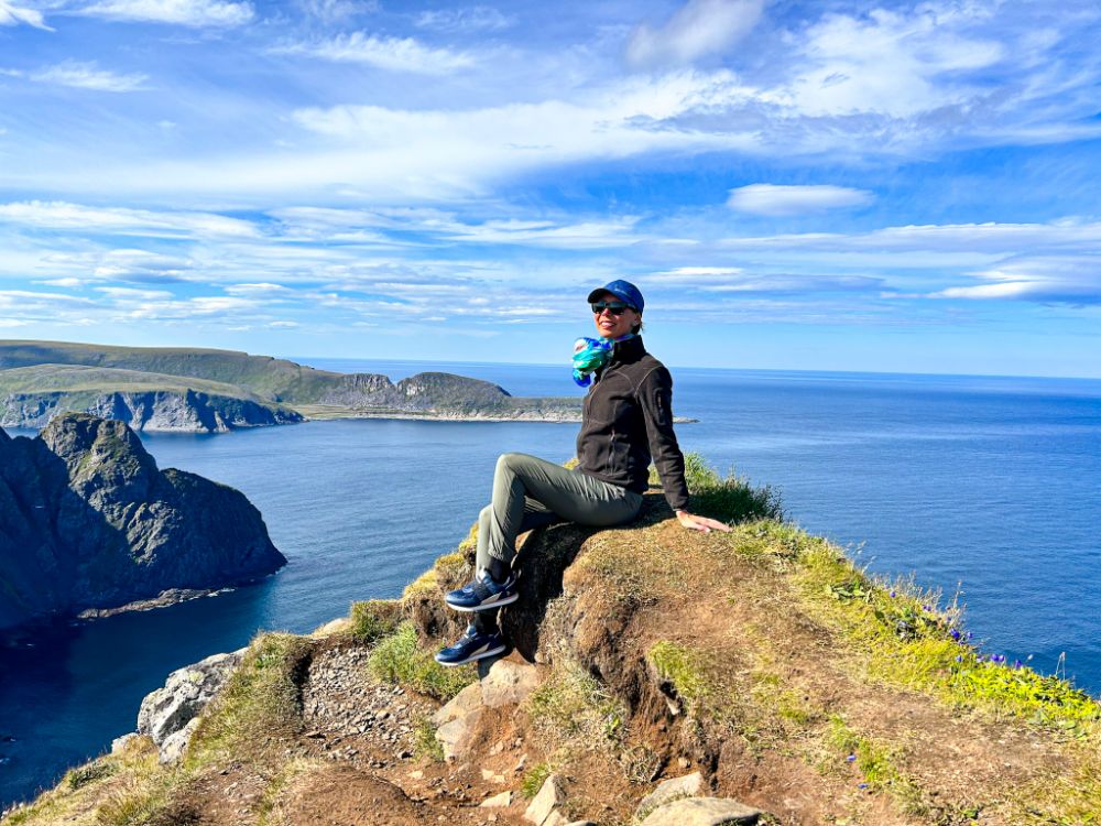 Ragazza mentre si gode il caldo sole diurno sulla scogliera di Capo Nord