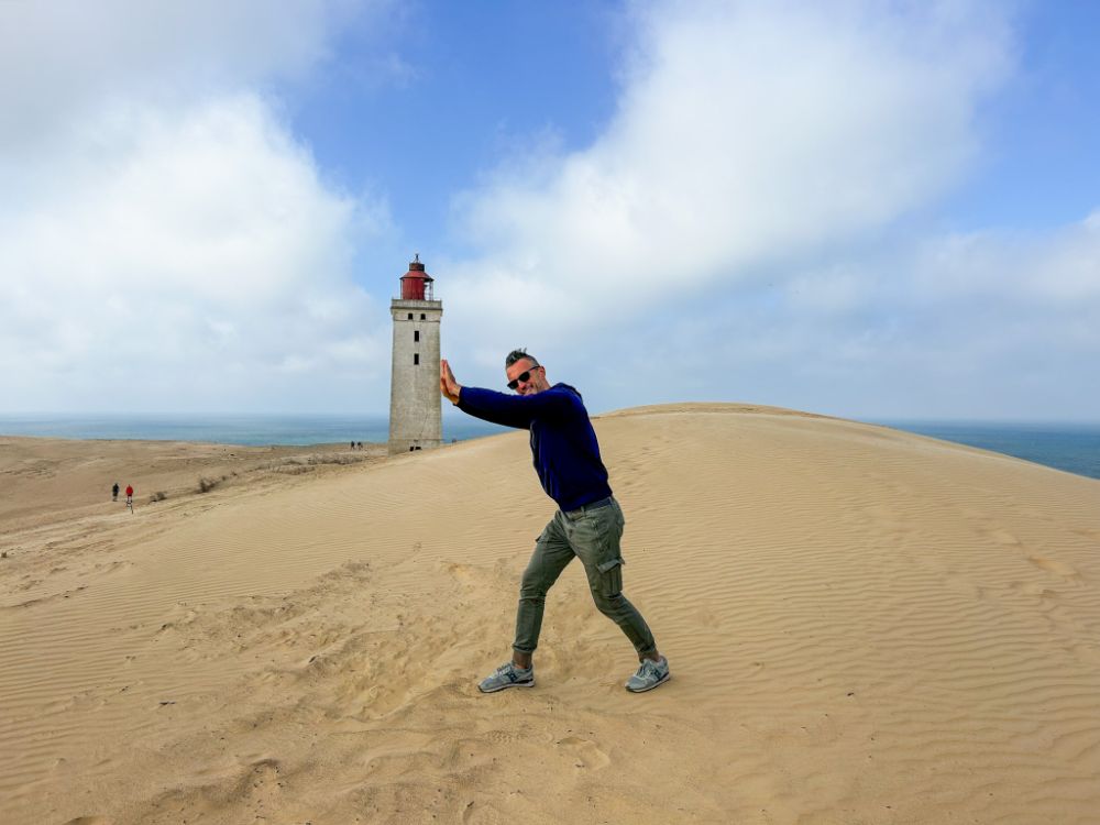 Il faro di Rubjerg Knude sorretto da un visitatore durante una posa divertente.